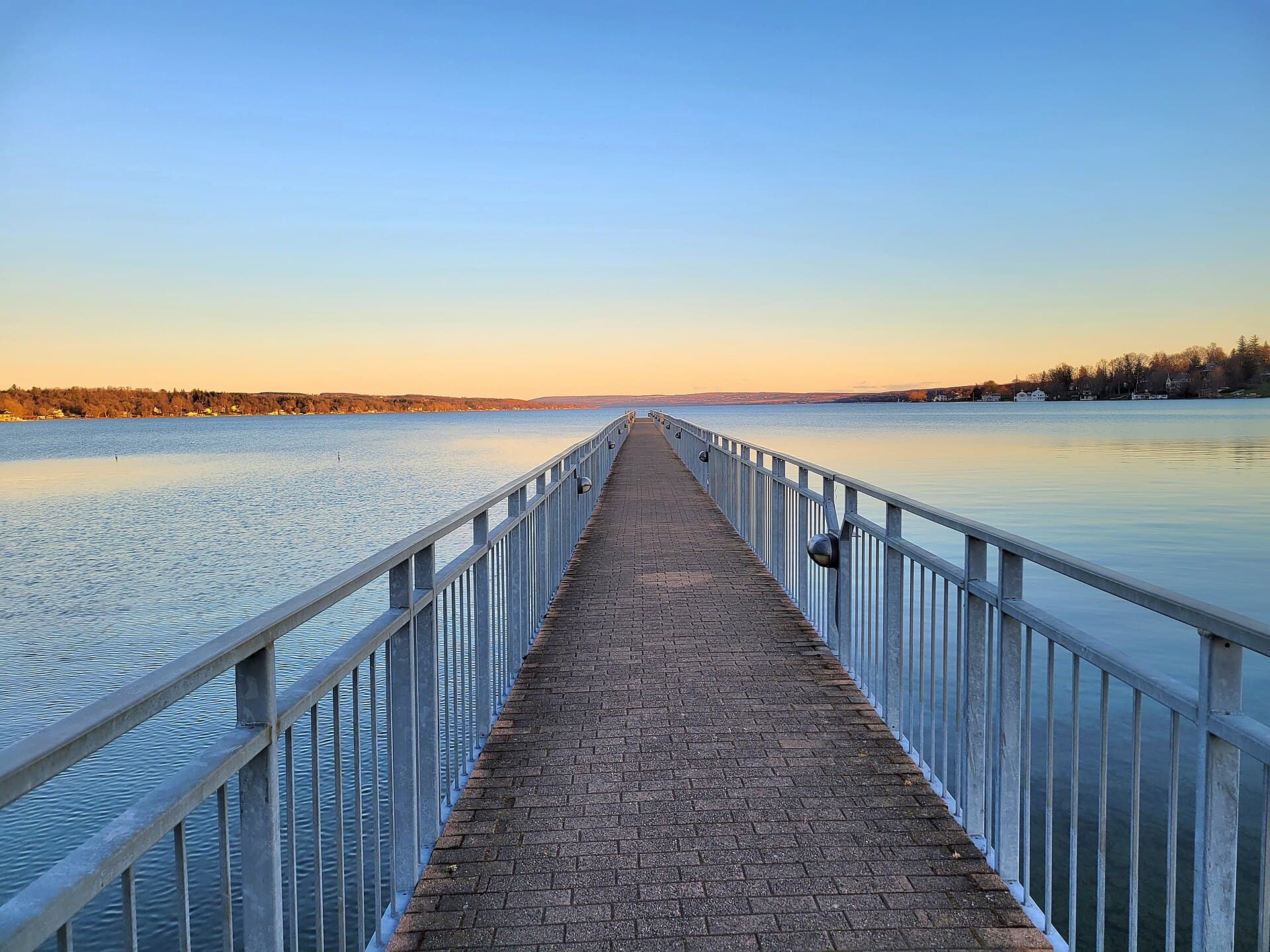 Skaneateles Village Pier extending into the clear lake at sunset